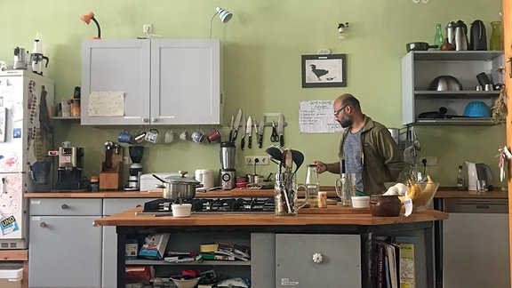 Eine graue Kücheninsel steht vor einer Küchenzeile