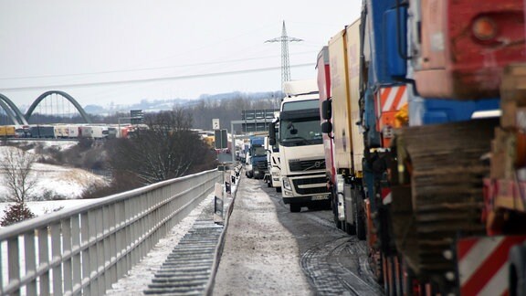 Lkw stauen sich auf einer verschneiten Autobahnbrücke