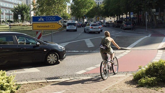 Auto lässt junge Person auf dem Fahrrad die Straße überqueren am Uniplatz in Magdeburg