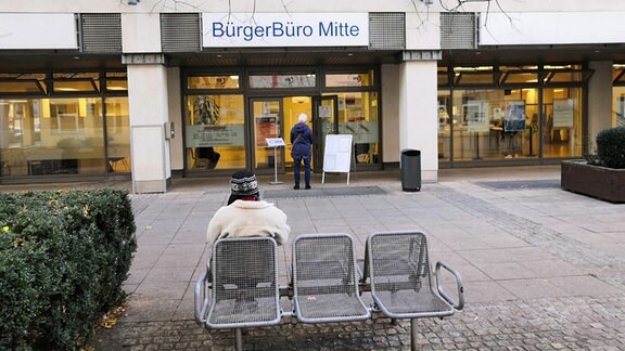 Das Bürgerbüro Mitte in Magdeburg von Außen. Oben steht die Aufschrift Bürgerbüro. Vor der Tür stehen eine ältere Dame und wartet.
