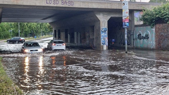 Autos fahren duch eine überflutete Unterführung in Magdeburg.