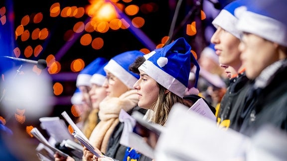 Ein Chor mit Liedblättern und blauen Weihnachtsmützen