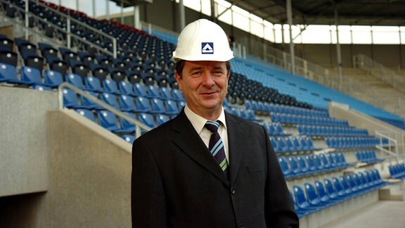 Magdeburgs Oberbürgermeister Lutz Trümper im Jahr 2006 mit einem Bauhelm auf dem Kopf in einem Stadion.