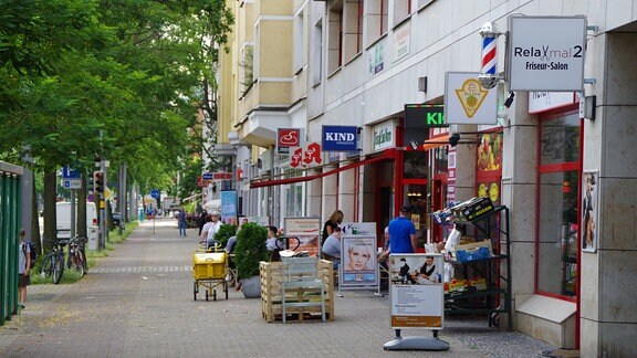 Blick die Lübecker Straße in der Neuen Neustadt herunter. Neben dem Fußweg: Viele bunte Ladenschilder von Friseuren, Apotheken, Bäckern, Banken, kleinen Gemüsemärkten und vielem mehr.