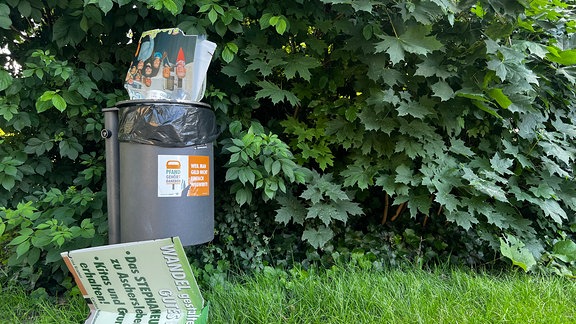 Mülleimer, in dem ein Wahlplakat steckt