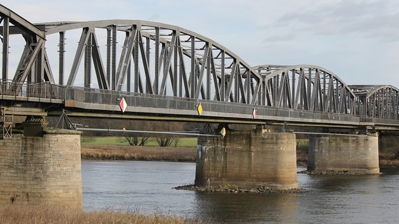 Eine graue Stahlbrücke in Fachwerkbauweise führt über die Elbe