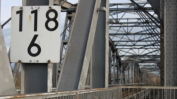 Eine graue Stahlbrücke in Fachwerkbauweise führt über die Elbe