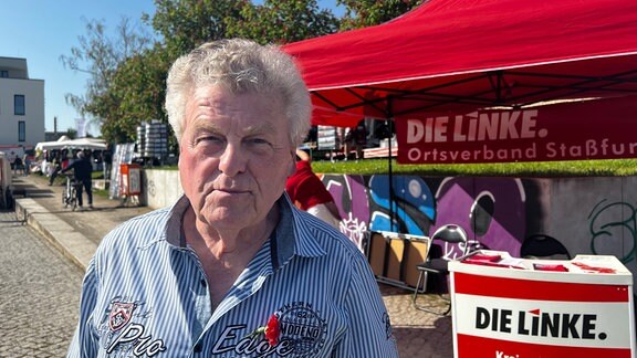 Ein älterer Mann steht vor einem Wahlstand in Staßfurt