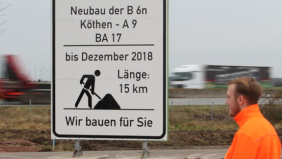 Ein Straßenbauer geht am 30.11.2015 in Thurland (Sachsen-Anhalt) an einem Schild vorbei. 