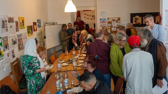 Viele Menschen in einem Raum mit gedecktem Tisch