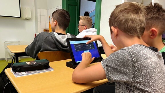 Schüler arbeiten mit Tablet im Unterricht. 