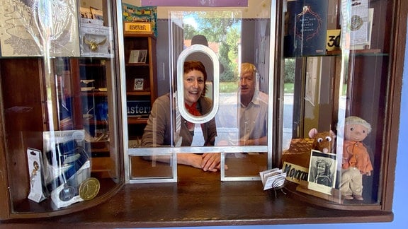 Eine Frau und ein Mann schauen aus einem Kartenverkaufshäusschen.