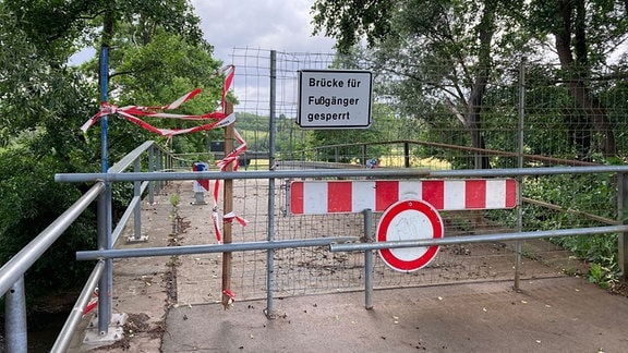 Auf einer Brücke stehen mehrere Schilder und Absperrungen.
