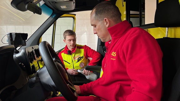 Zwei Männer vom Rettungsdienst im Rettungswagen