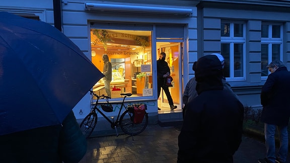 Schließung der Bäckerei Braune: Viele Kunden warten im Regen vor dem Laden.