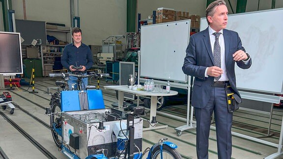 Projektleiter Tom Assmann und Staatsekretär Thomas Wünsch (SPD) aus den Wirtschaftsministerium stellen gemeinsam den aktuellen Forschungsstand zum autonomen Lastenfahrrad vor.