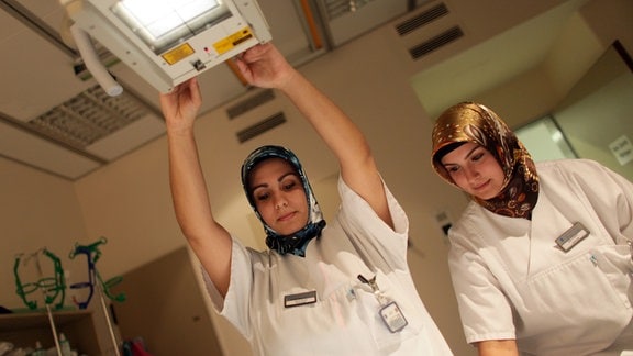Die medizinisch-technische Assistentinnen Gökce Simali (l) und Betül Caliscan tragen bei ihrer Arbeit in einem Lübecker Krankenhaus auf der Radiologie ein Kopftuch