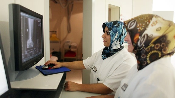 Die medizinisch-technische Assistentinnen Gökce Simali (l) und Betül Caliscan tragen bei ihrer Arbeit in einem Lübecker Krankenhaus auf der Radiologie ein Kopftuch, 2011.