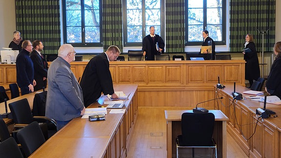 In einem Gerichtssaal stehen alle am Prozess beteiligten.