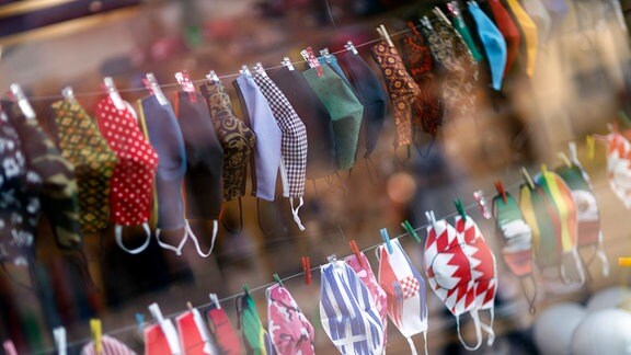 Stoffmasken im Schaufenster einer Schneiderei