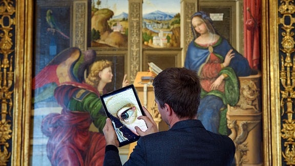 Ein Mitarbeiter schaut sich Details eines hochaufgelösten Fotos des Gemäldes "Verkündigung an Maria" im Bode-Museum auf einem Tablet an.