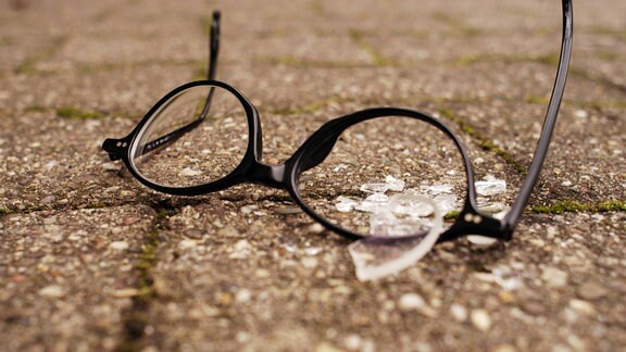 Zerbrochene Brille auf Straßenpflaster