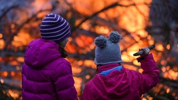 Zwei Mädchen stehen vor einem Osterfeuer