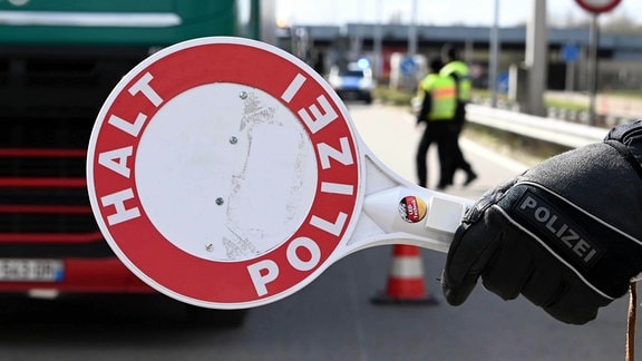 Ein Polizist stoppt mit seiner rote Kelle einen LKW. An der deutsch-französischen Grenze finden bei der Einreise nach Deutschland.