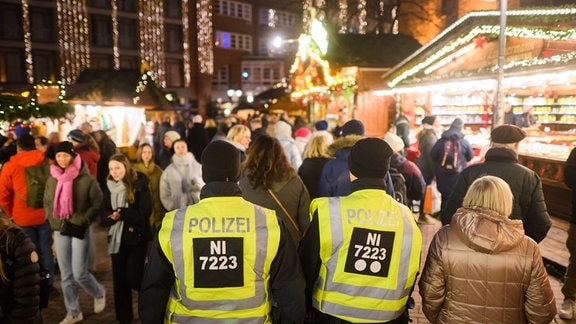 Polizisten gehen Streife auf einem Weihnachtsmarkt.