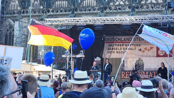 Eine Gruppe Demonstranten vor einer Bühne mit Oliver Kirchner.