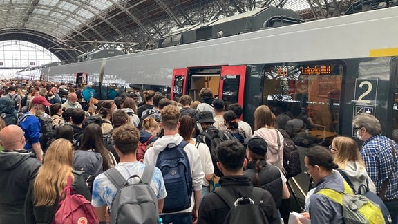 Viele Menschen drängen in eine Regionalbahn.