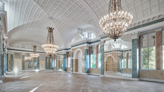 Blick in einen historischen Saal mit großen Kronleuchtern und vielen Spiegeln an den Wänden