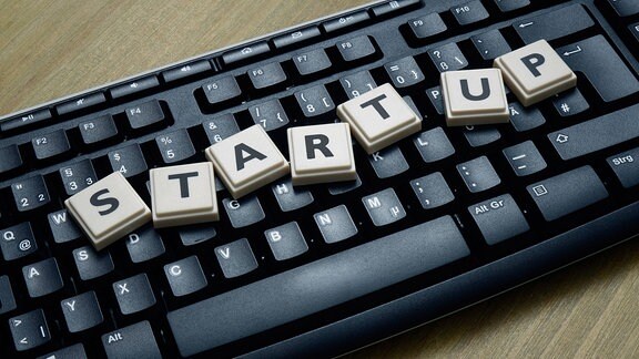 Auf einer Computertastatur liegt das Wort Start-up.