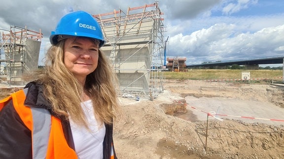 Eine Frau mit roter Warnweste und blauem Bauhelm