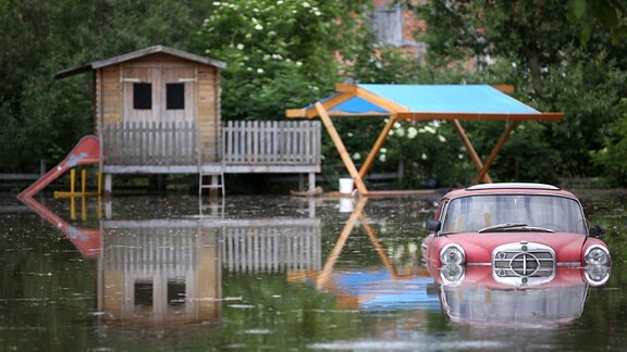 Ein Oldtimer steht am 11.06.2013 auf einem überfluteten Grundstück im vom Hochwasser eingeschlossenen Schönhausen (Sachsen-Anhalt).