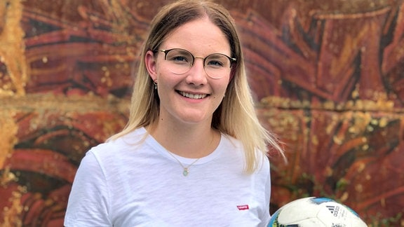Blonde junge Frau mit Fußball in weißem T-Shirt