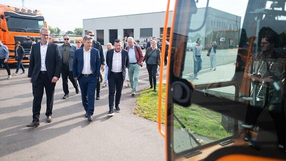 Robert Habeck (Bündnis 90/Die Grünen, M), Bundesminister für Wirtschaft und Klimaschutz, geht während eines Besuchs des Bauunternehmens Ost Bau im Rahmen seiner Sommerreise mit Henning Klapötke (l), Geschäftsführer Ost Bau, und Lars-Uwe Wimmer, Geschäftsführer Ost Bau, zu einem Baufahrzeug.