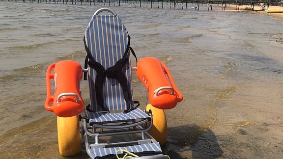Ein besonderer Rollstuhl mit extra breiten Reifen, der zum Baden im See geeignet ist.