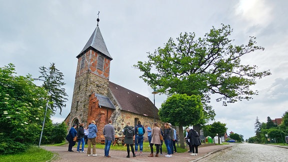 Eine Gruppe Menschen steht vor einer Kirche