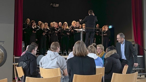 Eine Gesprächsgruppe sitzt im Zuschauerraum eines Chorauftrittes.