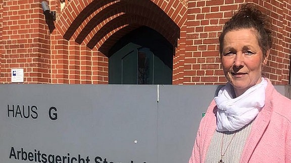 Lehrerin Birgit Pitschmann steht in rosa Cardigan vor dem Amts- und Arbeitsgericht Stendal
