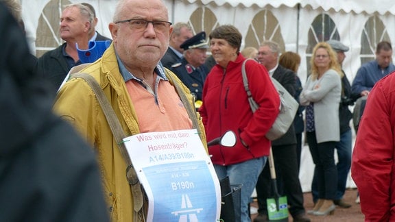 Ein Befürworter der sogenannten Hosenträgervariante mit einem Schild um den Hals: "Was wird mit dem Hosenträger? A14/A39/B190n"