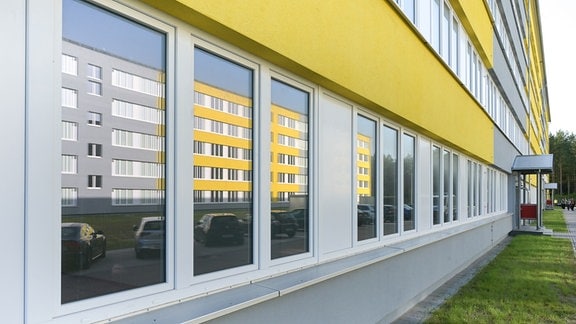 In einem Fenster spiegelt sich ein Wohngebäude der Landesaufnahmestelle für Geflüchtete in Standal.