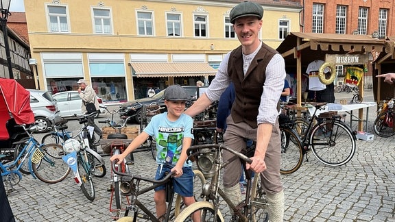 Ein Vater und sein Sohn in geschichtsträchtiger Kleidung beim Vintage-Fahrradrennen in Tangermünde. 