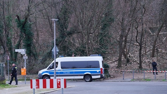 Polizeibeamte und ein Einsatzfahrzeug stehen vor dem Volkspark Prenzlauer Berg. 
