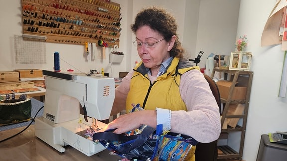 Eine Frau sitzt an einer Nähmaschine.