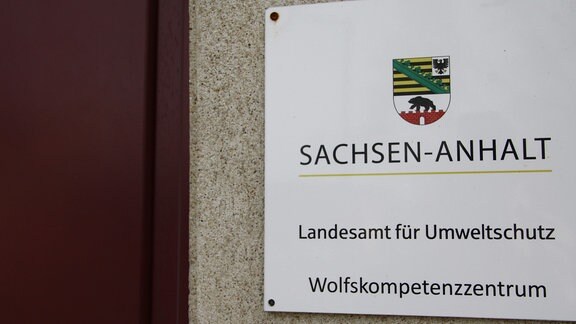Weißes Hinweisschild mit dem Logo von Sachsen-Anhalt und der Aufschrift -Landesamt für Umweltschutz Wolfskompetenzzentrum-