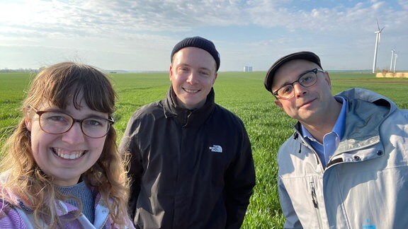 Eine Frau und zwei Männer auf einem Feld