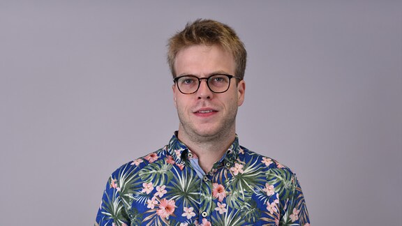 Ein junger Mann mit Brille und buntem Hemd
