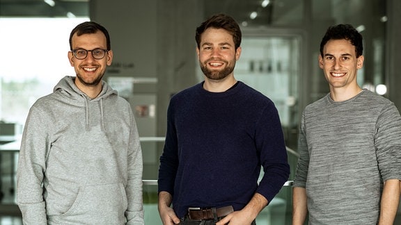 Drei Männer vom Entwicklerteam VOTO Magdeburg lächeln in die Kamera.